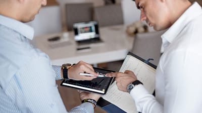 Deux professionnels examinant des graphiques financiers sur une tablette lors d'une réunion d'affaires.