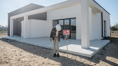 Agent immobilier avec casque debout près d'une maison moderne à vendre.