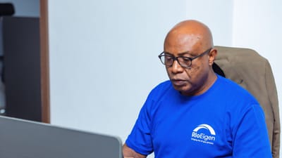 Un homme adulte en chemise bleue travaillant sur un ordinateur portable à un bureau.
