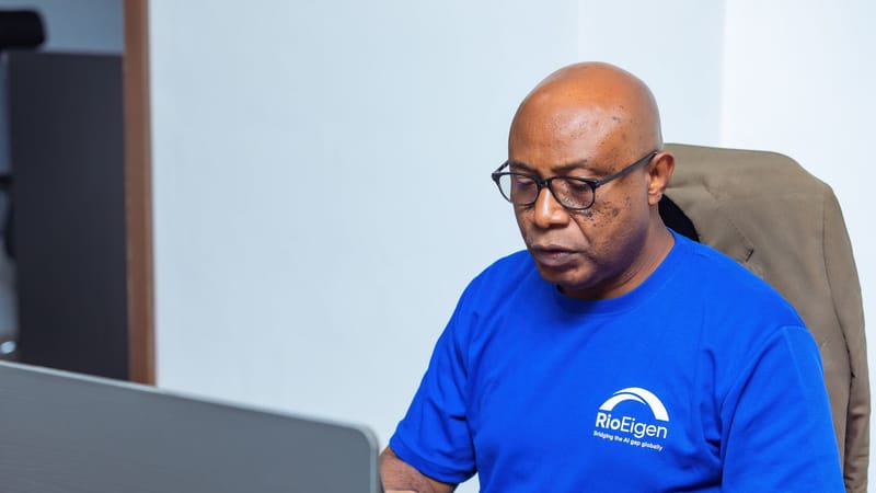Un homme adulte en chemise bleue travaillant sur un ordinateur portable à un bureau.