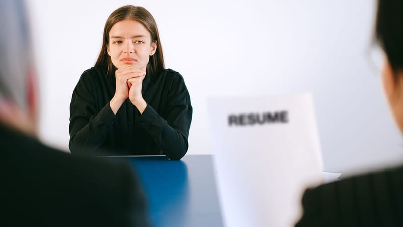 Une femme en entretien d'embauche face à deux employeurs avec un accent sur son CV.