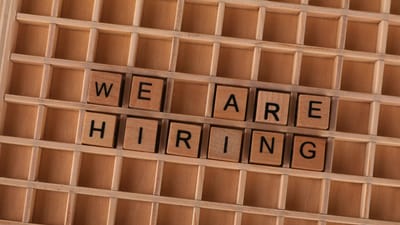 Panneau de tuiles en bois formant la phrase « Nous recrutons », idéal pour les annonces d'emploi.