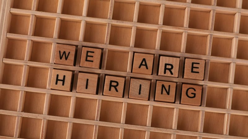 Panneau de tuiles en bois formant la phrase « Nous recrutons », idéal pour les annonces d'emploi.