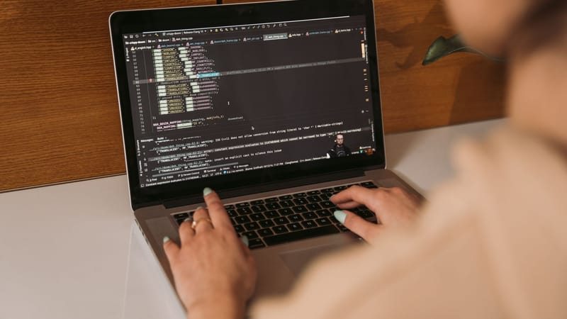 Gros plan d'une femme codant avec un ordinateur portable dans un environnement de bureau, mettant en avant la technologie moderne.