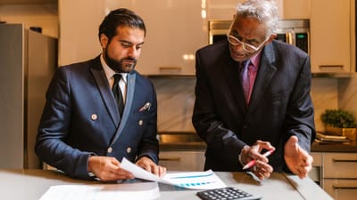 Deux hommes d'affaires engagés dans une discussion concentrée autour de documents financiers dans un bureau moderne.