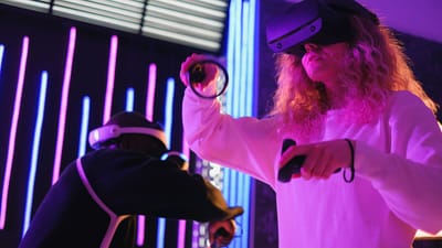 Deux personnes profitant d'une expérience de jeu VR immersive à l'intérieur avec des lumières néon.