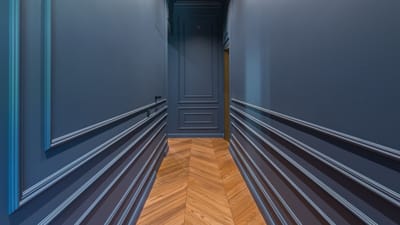 Un couloir élégant avec des murs bleus et un sol en bois au motif en chevrons.