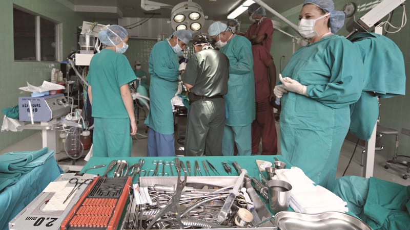 Équipe médicale effectuant une chirurgie dans une salle d'opération stérile avec des instruments chirurgicaux au display.