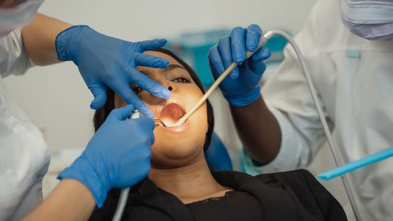 Des professionnels de la santé dentaire effectuant un examen approfondi d'un patient dans un cadre clinique, mettant l'accent sur les soins de santé.