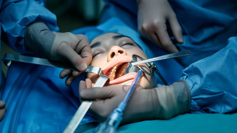 Des professionnels de la santé effectuant une chirurgie dentaire sur un patient dans un cadre de clinique.
