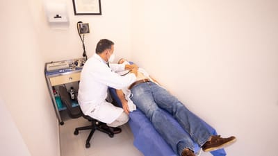 Professionnel de santé examine le patient avec un stéthoscope dans une salle d'examen clinique.