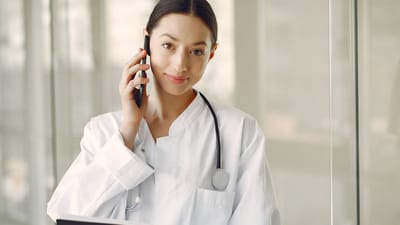 Médecin femme professionnelle en blouse blanche parlant au téléphone dans une clinique médicale.