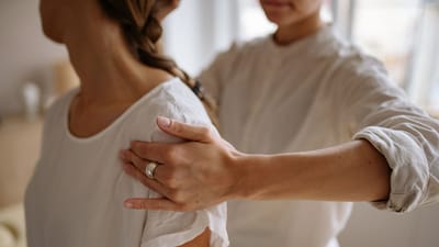 Vue détaillée d'une séance de physiothérapie avec placement de la main sur l'épaule à l'intérieur.