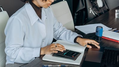 Jeune femme dans un bureau utilisant une calculatrice pour des calculs financiers.