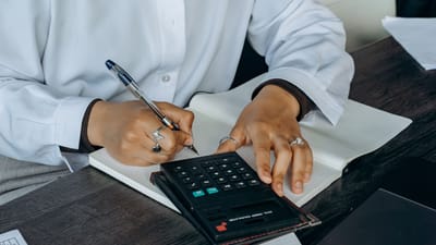 Gros plan sur un professionnel prenant des notes avec une calculatrice à un bureau en bois.