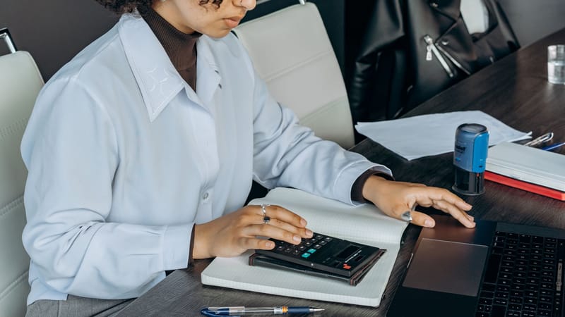 Jeune femme dans un bureau utilisant une calculatrice pour des calculs financiers.