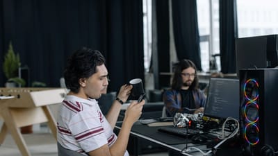 Deux programmeurs au travail dans un bureau moderne, concentrés sur le codage et profitant d'une pause café.
