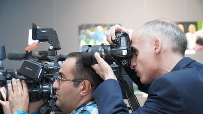 Photographes se concentrant sur la couverture d'événements avec des appareils photo avancés en intérieur, montrant des professionnels des médias en action.