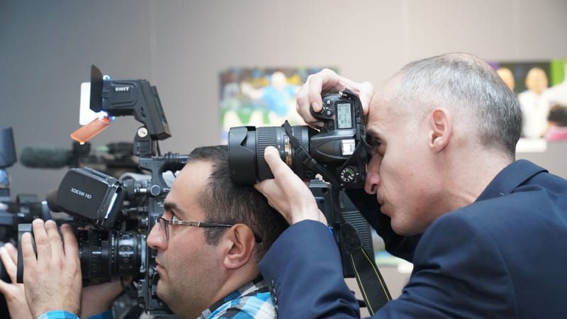 Photographes se concentrant sur la couverture d'événements avec des appareils photo avancés en intérieur, montrant des professionnels des médias en action.