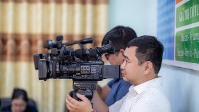 Cameraman masculin utilisant une caméra vidéo professionnelle lors d'un événement en intérieur.