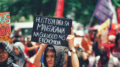 Des manifestants se sont rassemblés à l'extérieur tenant des panneaux réclamant la justice économique et les droits des travailleurs.