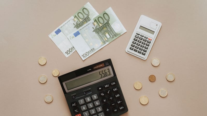 Vue de dessus de calculatrices et de la monnaie Euro, illustrant les calculs financiers et la gestion de budget.