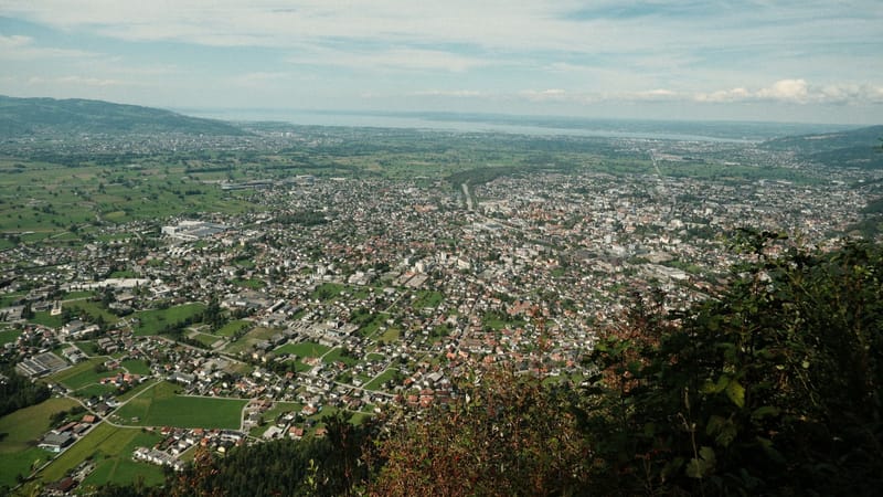 Vaste vue panoramique sur une ville entourée de verdure sous un ciel dégagé.