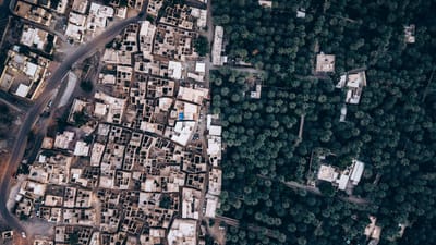 Superbes images aériennes de maisons traditionnelles en terre et de luxuriantes palmeraies à Oman, illustrant un contraste saisissant entre milieu urbain et nature.