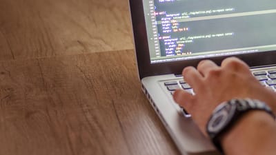 Gros plan sur une personne qui code sur un ordinateur portable, mettant en avant le développement web et les concepts de programmation.