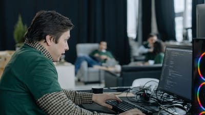 Programmeur masculin se concentrant sur le codage à l'ordinateur dans un environnement de bureau contemporain.