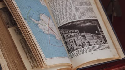 Gros plan détaillé d'un livre d'histoire ouvert montrant une carte vintage et une illustration.