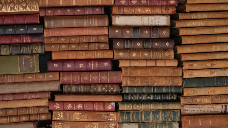Pile de livres vintage en cuir avec des designs ornés, reflétant l'histoire et la littérature.