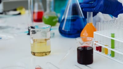 Liquides colorés dans des verreries de laboratoire et des éprouvettes lors d'une expérience scientifique.