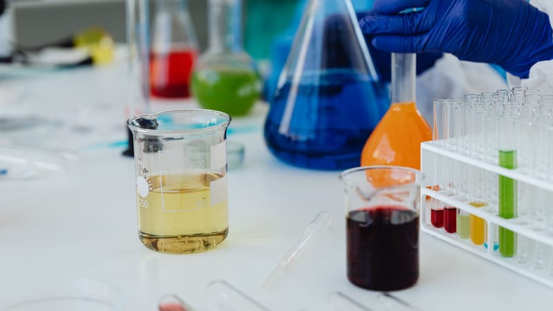 Liquides colorés dans des verreries de laboratoire et des éprouvettes lors d'une expérience scientifique.