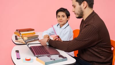 Un enseignant assiste un élève dans une salle de classe colorée, favorisant l'apprentissage et l'éducation.