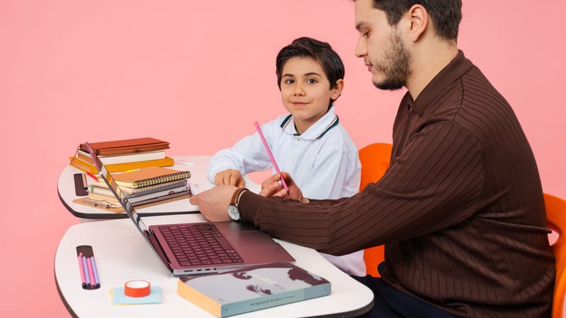 Un enseignant assiste un élève dans une salle de classe colorée, favorisant l'apprentissage et l'éducation.
