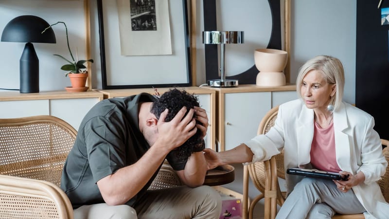 Un thérapeute bienveillant apporte du réconfort lors d'une séance de conseil dans un bureau chaleureux.