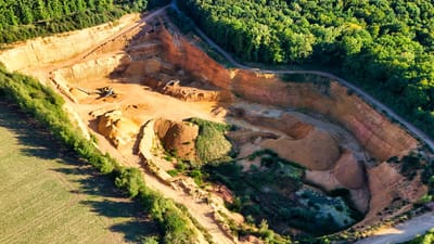 Une magnifique vue aérienne d'une grande carrière en contraste avec de luxuriantes forêts vertes.