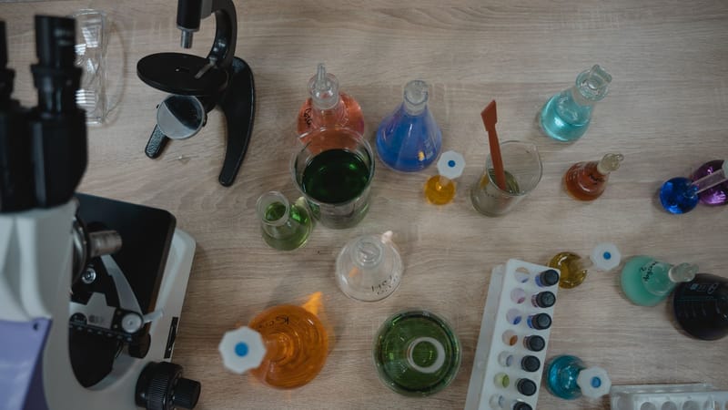 Laboratoire de chimie coloré avec des tubes à essai et un microscope vu de dessus.