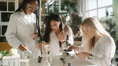 Trois femmes scientifiques multiculturelles s'engagent dans des expériences de laboratoire avec des microscopes et du matériel en verre.