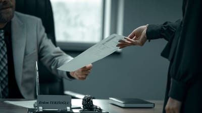 Une interaction professionnelle formelle avec échange de documents entre des professionnels dans un cadre de bureau moderne.