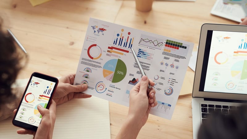 Les membres de l'équipe analysent des graphiques lors d'une réunion d'affaires avec des ordinateurs portables et des smartphones.