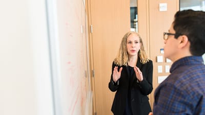 Deux professionnels discutent d'idées autour d'un tableau blanc au travail. Réunion d'équipe collaborative.