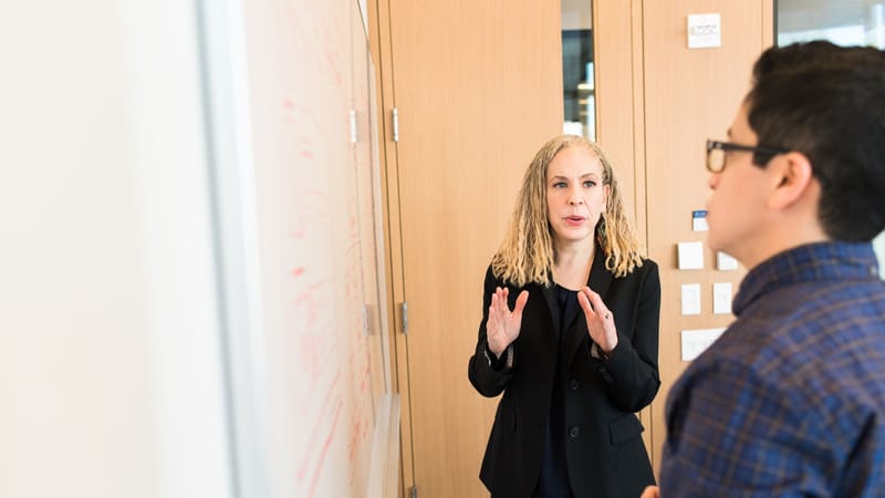 Deux professionnels discutent d'idées autour d'un tableau blanc au travail. Réunion d'équipe collaborative.