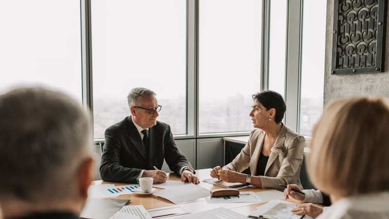 Des professionnels des affaires engagés dans une réunion stratégique dans un bureau moderne avec lumière naturelle.