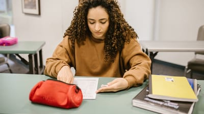 Jeune femme étudiant pour un examen dans une salle de classe universitaire avec des livres et des notes.