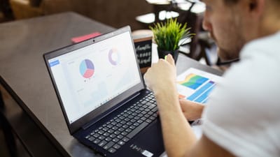 Homme examinant des graphiques et des tableaux sur un ordinateur portable pour une analyse commerciale.