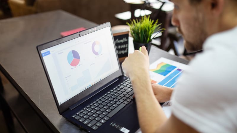 Homme examinant des graphiques et des tableaux sur un ordinateur portable pour une analyse commerciale.
