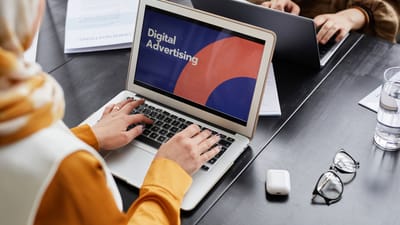 Deux professionnels travaillent sur des ordinateurs portables en se concentrant sur la publicité numérique dans un cadre de bureau.