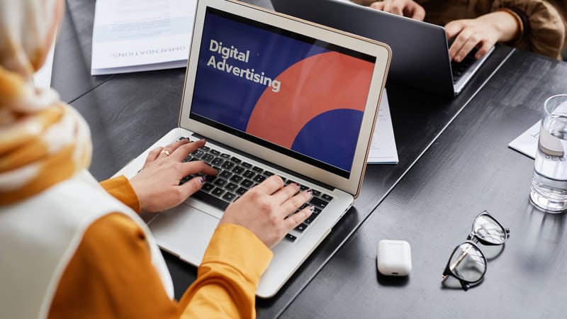 Deux professionnels travaillent sur des ordinateurs portables en se concentrant sur la publicité numérique dans un cadre de bureau.